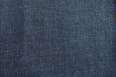 Photo of Texture of dark blue jeans as background, top view