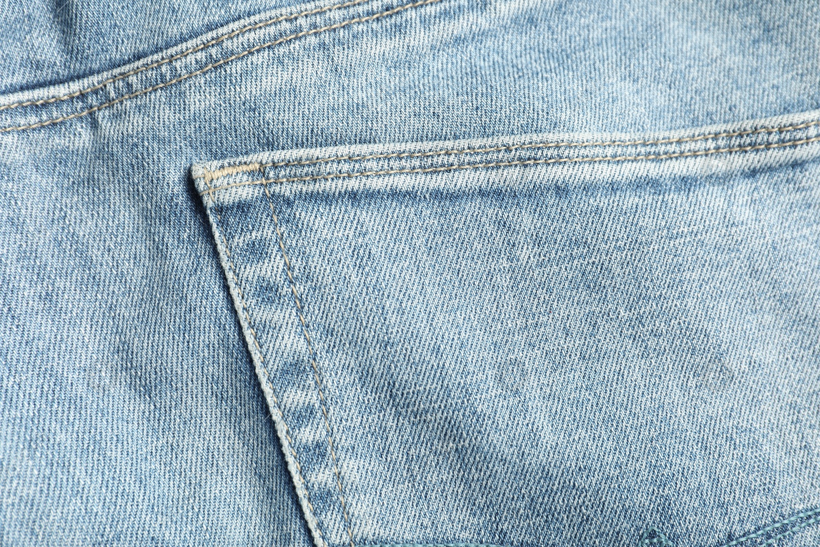 Photo of Stylish light blue jeans with pocket as background, top view