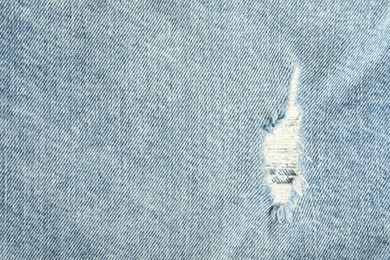 Photo of Texture of ripped light blue jeans as background, top view