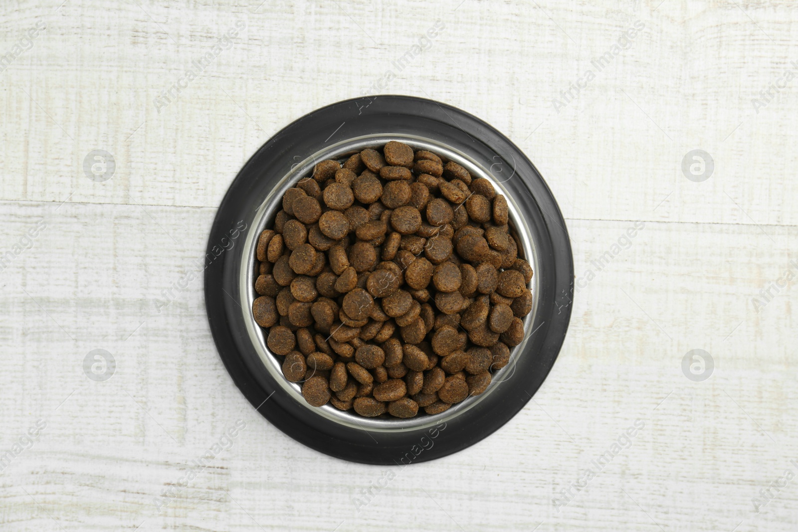 Photo of Dry pet food in feeding bowl on floor, top view