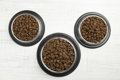 Photo of Dry pet food in feeding bowls on floor, flat lay