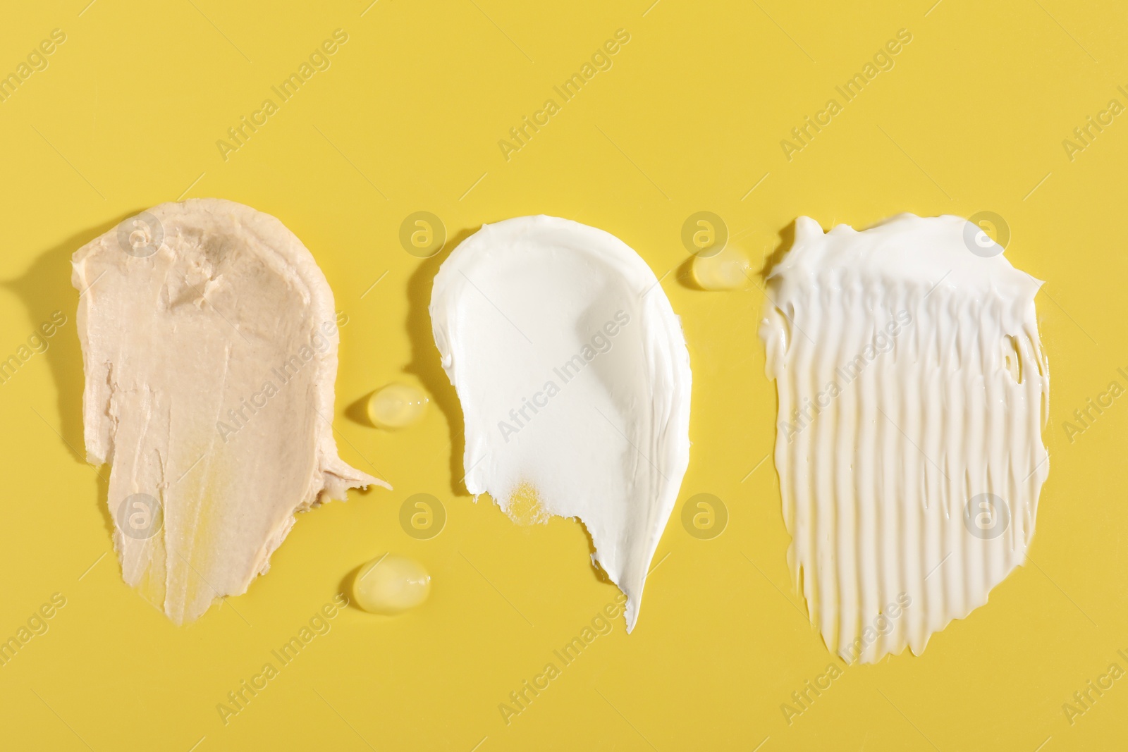 Photo of Samples of different cosmetic products on yellow background, flat lay