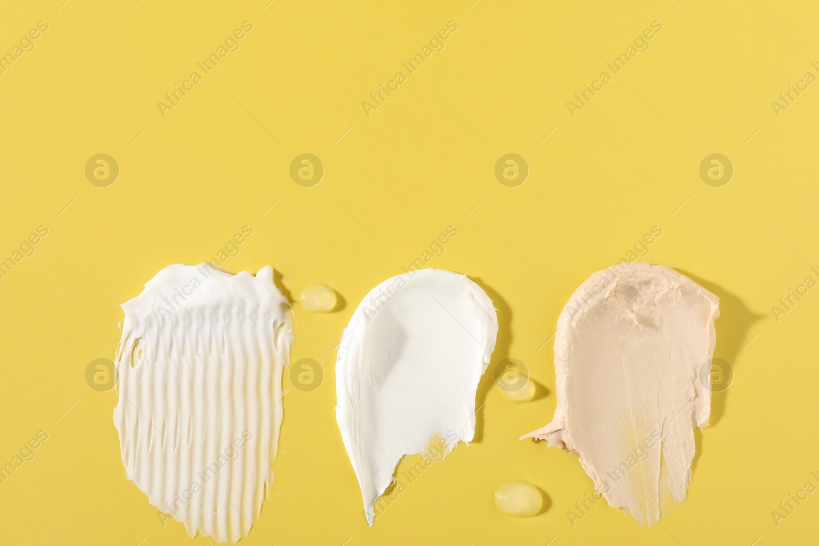 Photo of Samples of different cosmetic products on yellow background, flat lay. Space for text