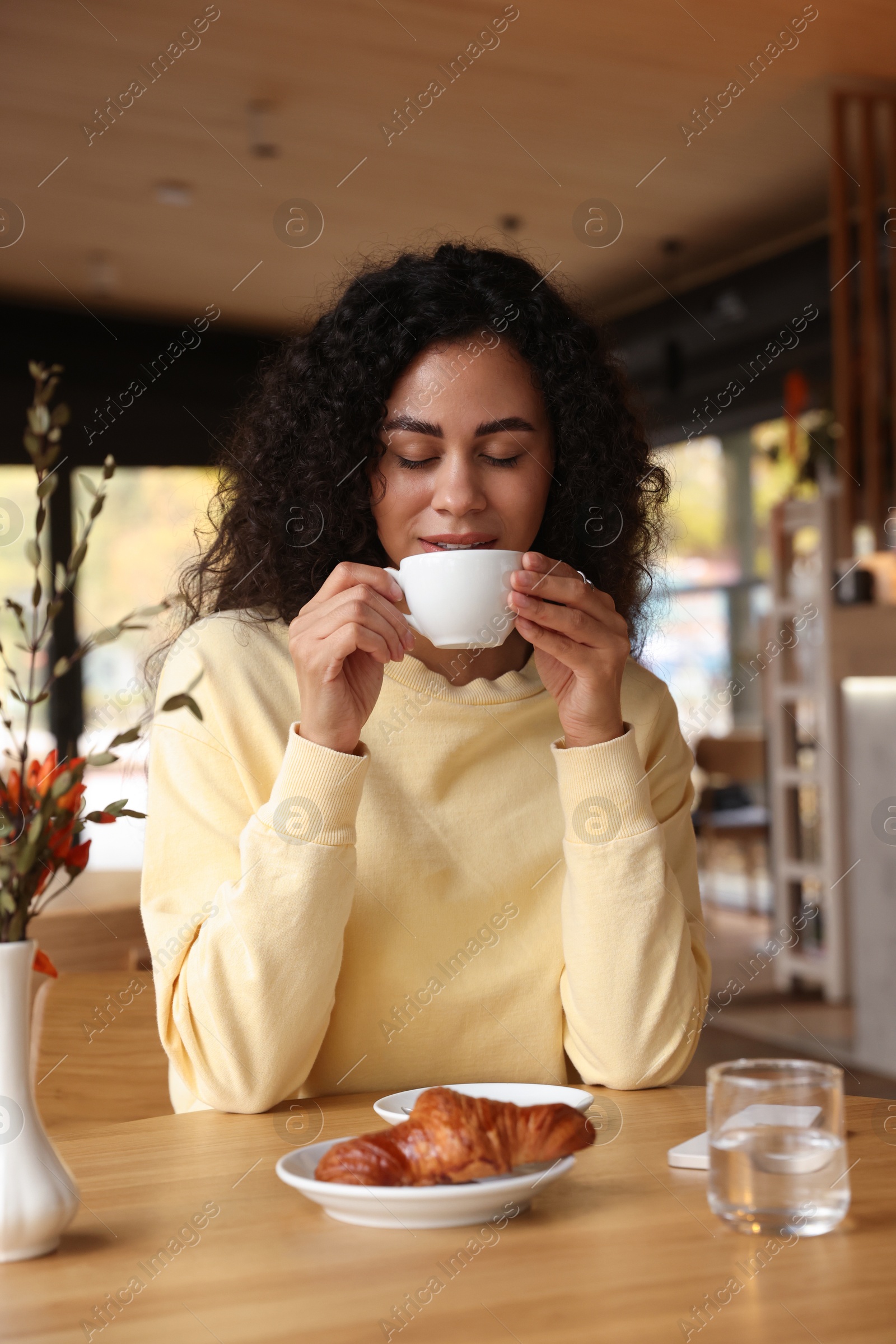 Photo of Woman enjoying her aromatic coffee at table in cafe