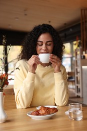 Woman enjoying her aromatic coffee at table in cafe