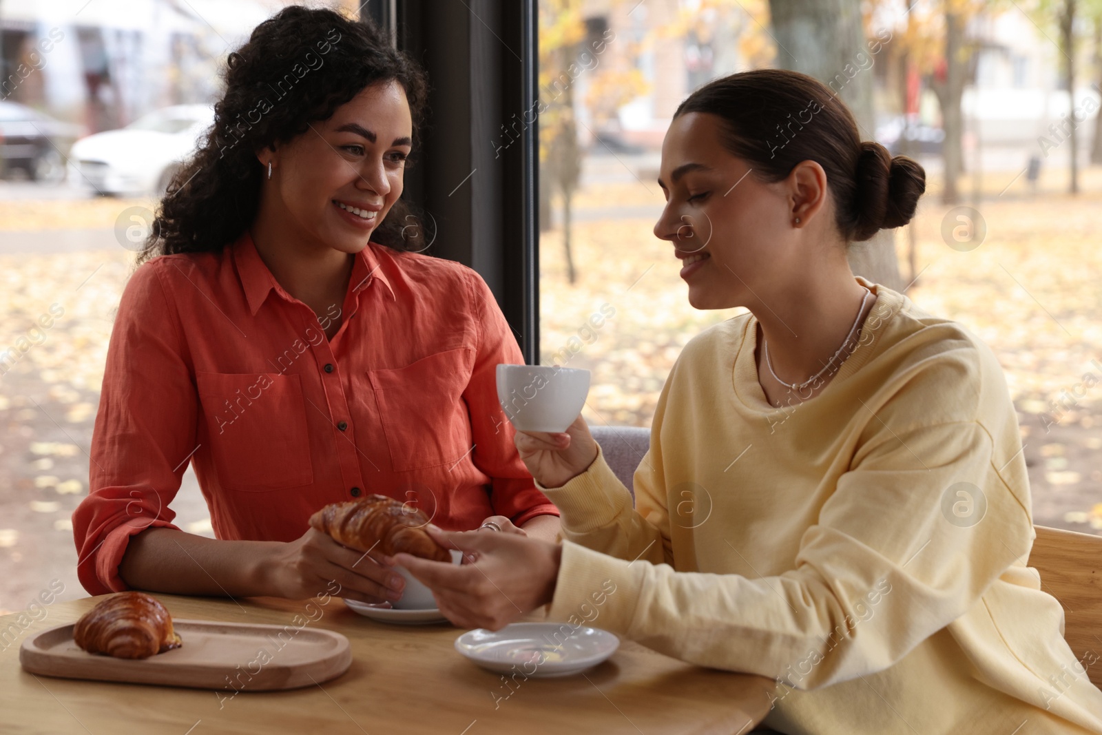 Photo of Happy women with coffee drinks chatting in cafe