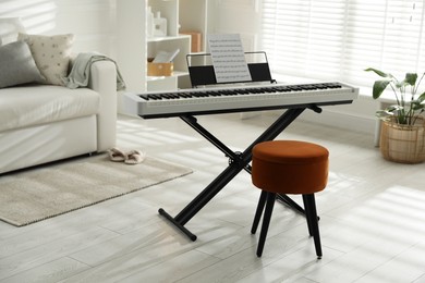 Photo of Synthesizer with music sheet and pouf at home