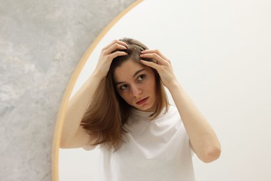 Photo of Girl with hair loss problem near mirror in bathroom, space for text