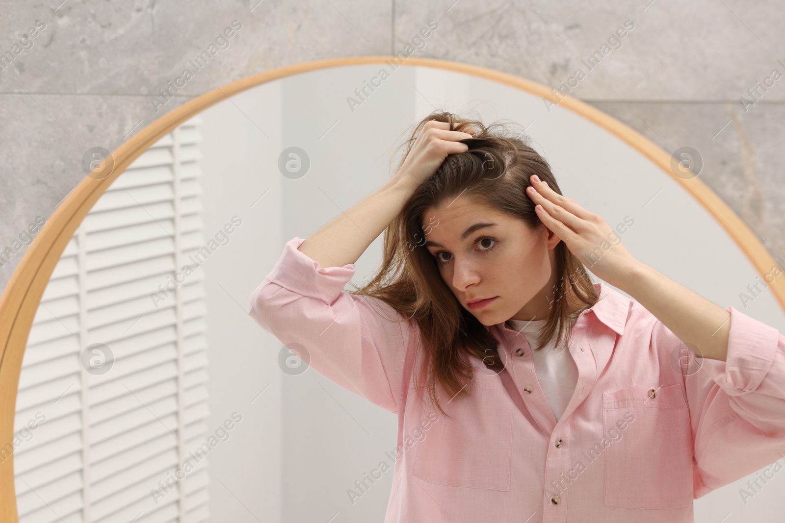 Photo of Girl with hair loss problem near mirror in bathroom