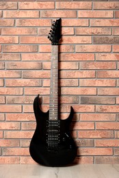 Photo of One modern electric guitar near brick wall