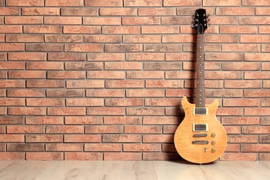 Photo of One modern electric guitar near brick wall. Space for text