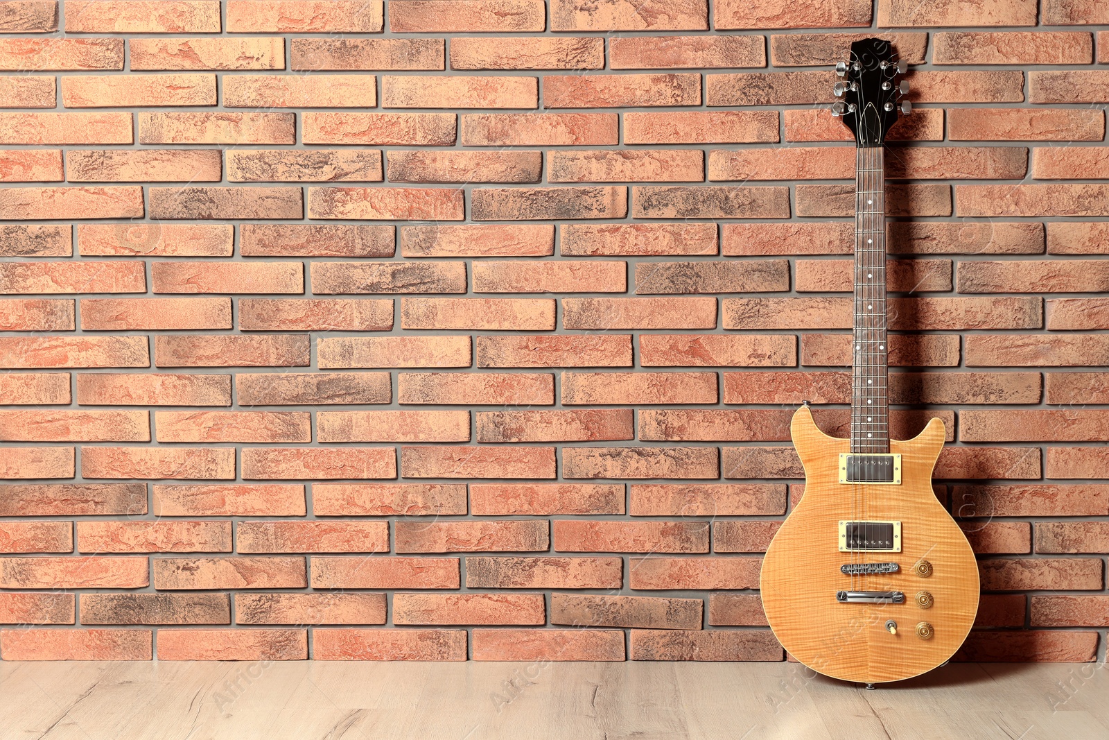 Photo of One modern electric guitar near brick wall. Space for text