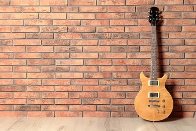 Photo of One modern electric guitar near brick wall. Space for text