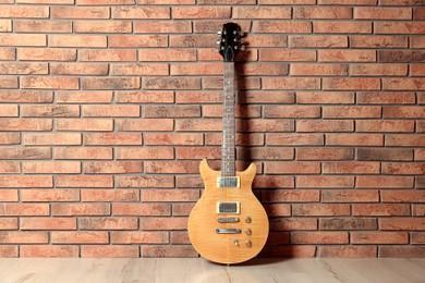 Photo of One modern electric guitar near brick wall. Space for text