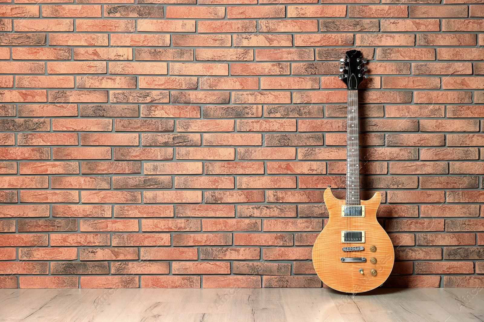 Photo of One modern electric guitar near brick wall. Space for text