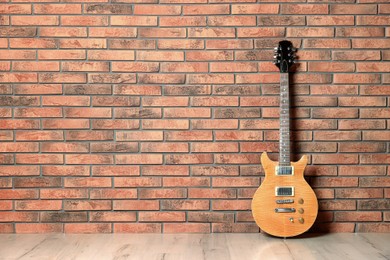 One modern electric guitar near brick wall. Space for text