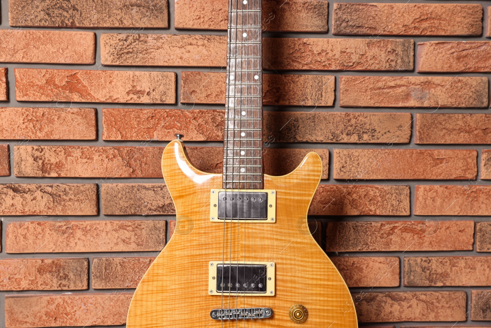 Photo of One modern electric guitar near brick wall, closeup