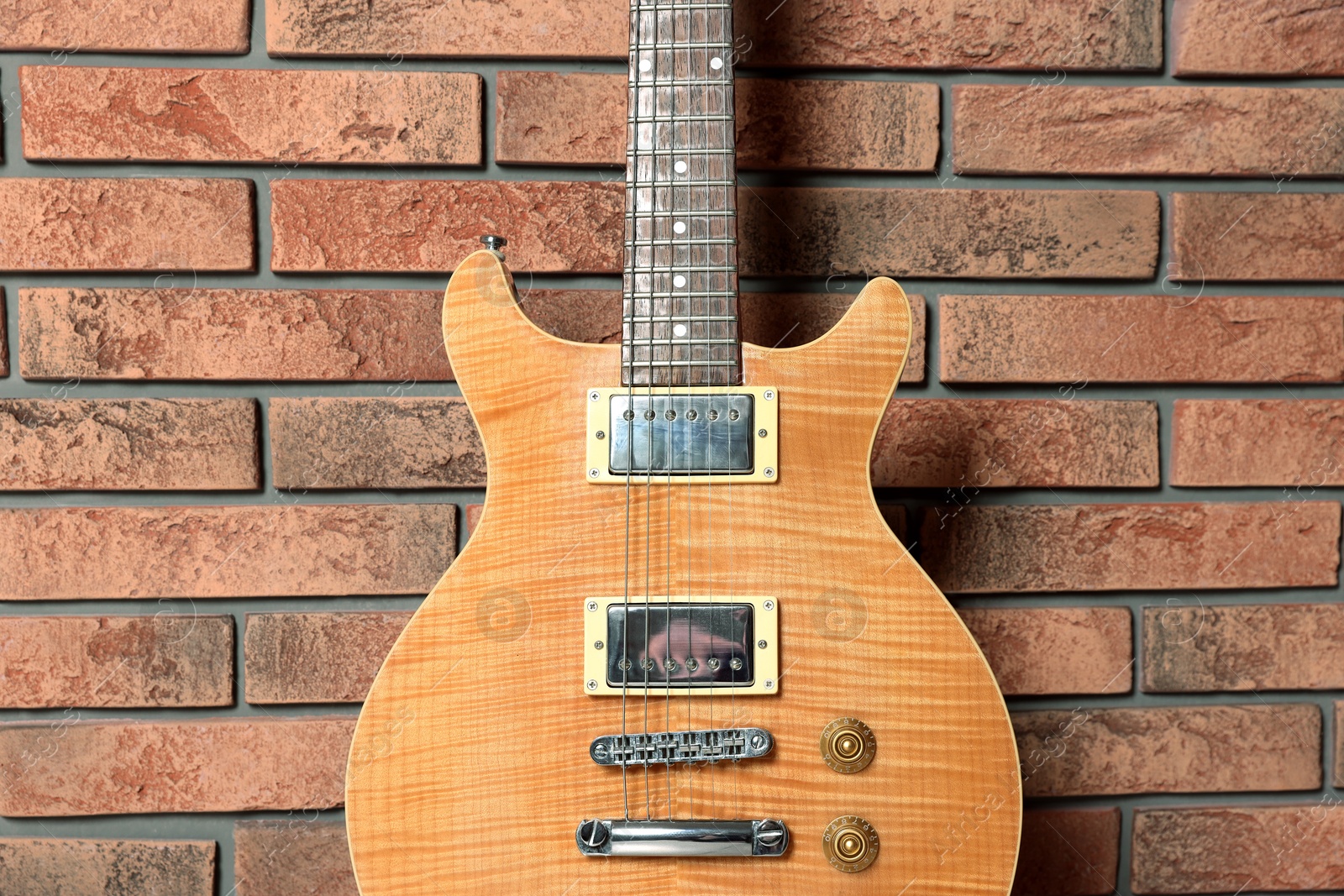 Photo of One modern electric guitar near brick wall, closeup