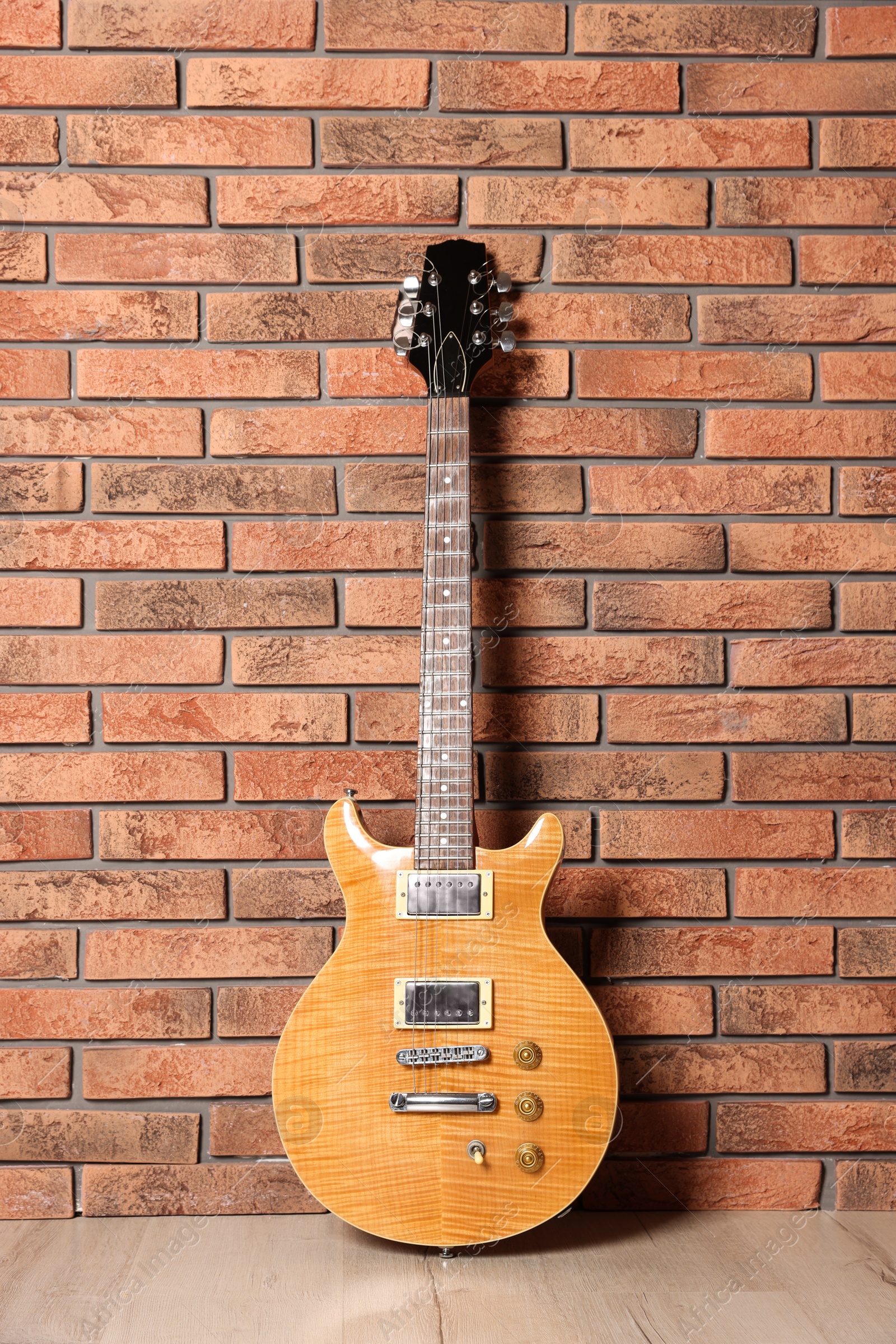 Photo of One modern electric guitar near brick wall