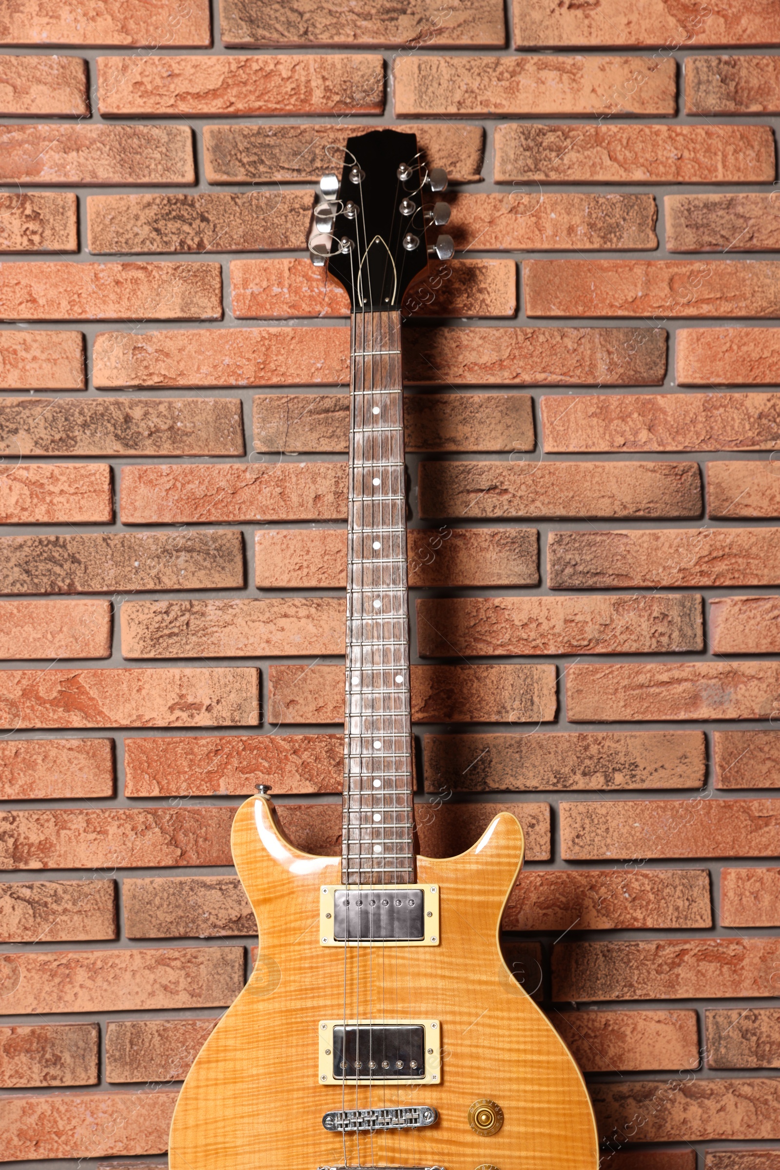 Photo of One modern electric guitar near brick wall