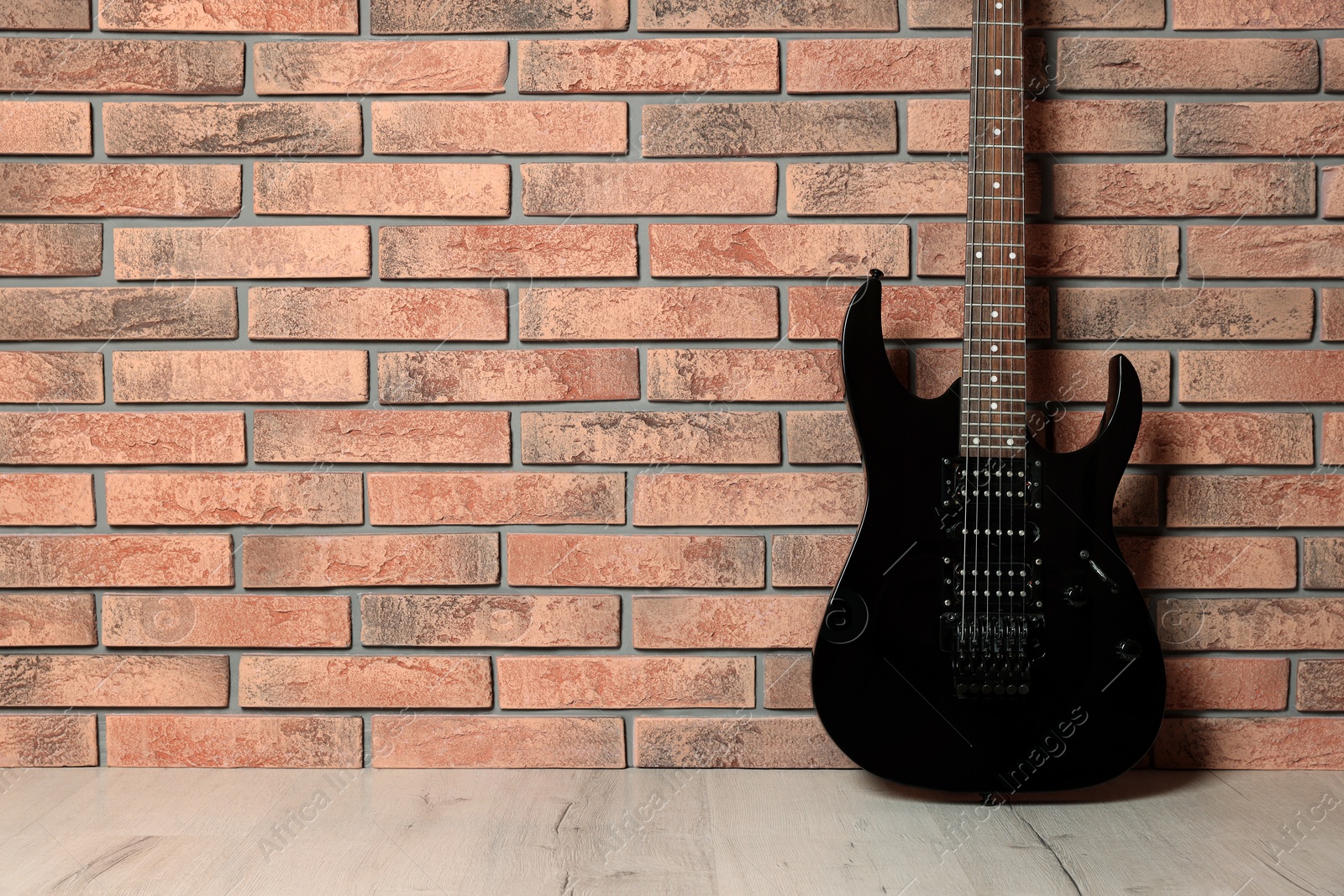 Photo of One modern electric guitar near brick wall. Space for text