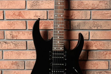 Photo of One modern electric guitar near brick wall, closeup