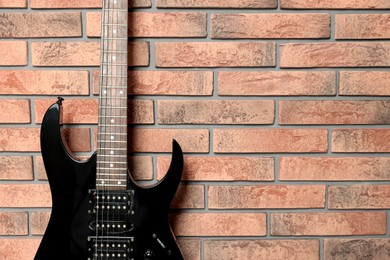 Photo of One modern electric guitar near brick wall, closeup. Space for text