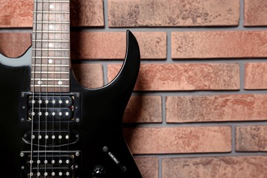 Photo of One modern electric guitar near brick wall, closeup. Space for text