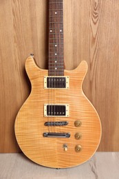 One modern electric guitar near wooden wall