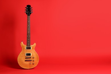 Photo of One modern electric guitar on red background. Space for text