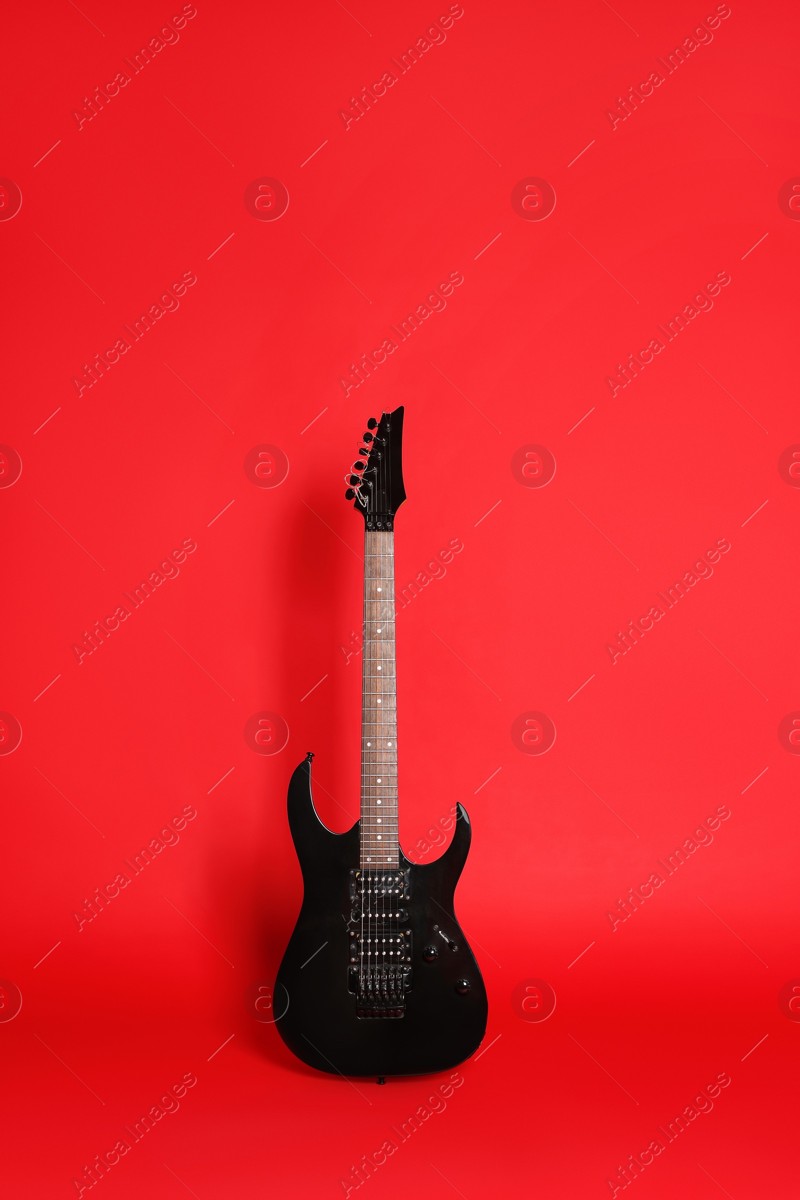 Photo of One modern electric guitar on red background