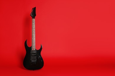 Photo of One modern electric guitar on red background. Space for text