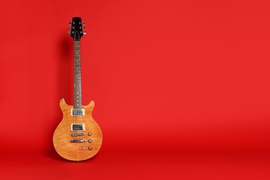 Photo of One modern electric guitar on red background. Space for text