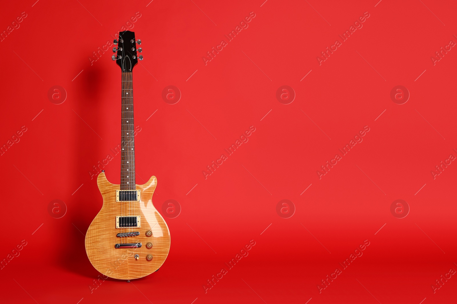 Photo of One modern electric guitar on red background. Space for text