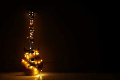 Electric guitar with Christmas lights on dark background. Space for text