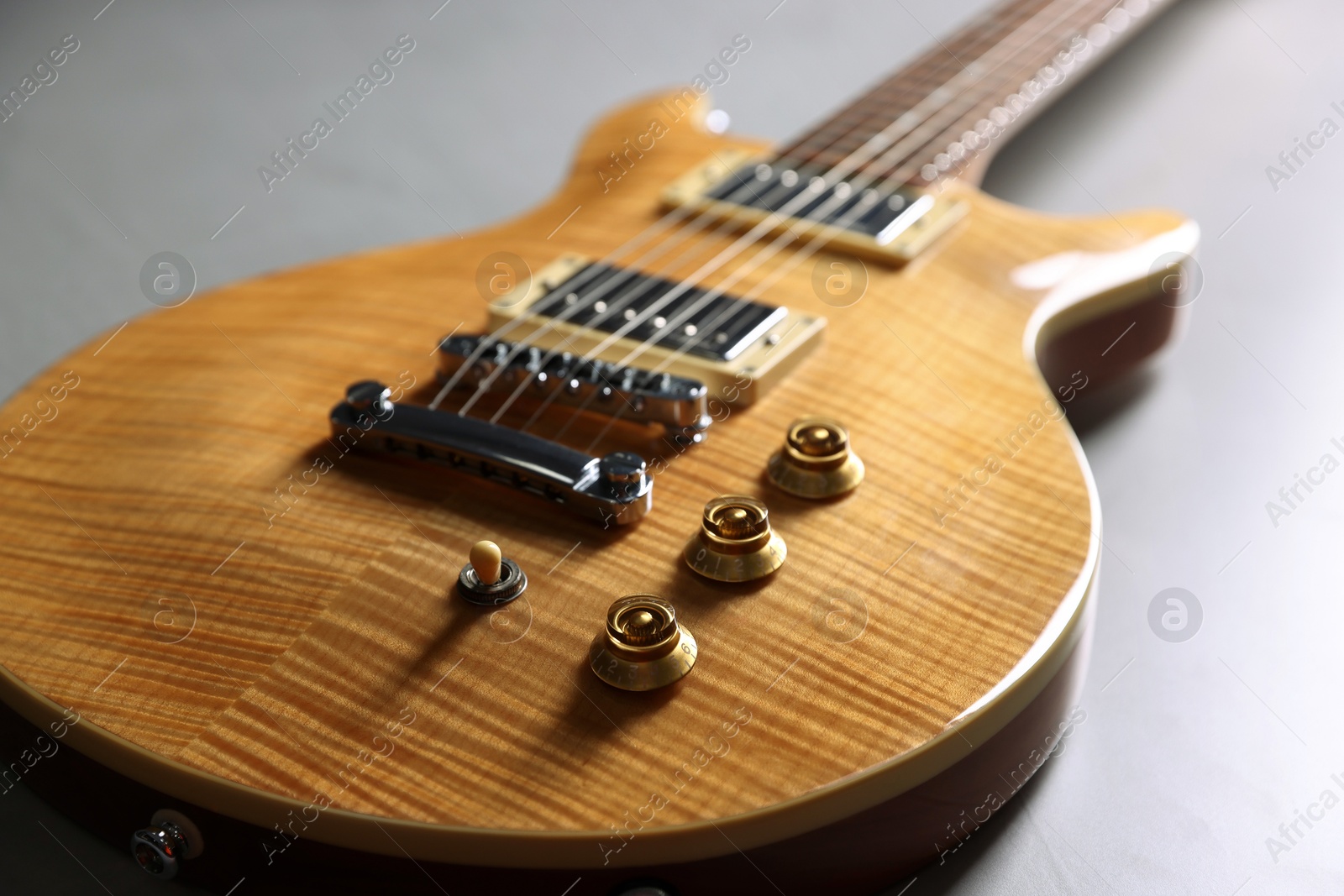 Photo of Modern electric guitar on grey background, closeup