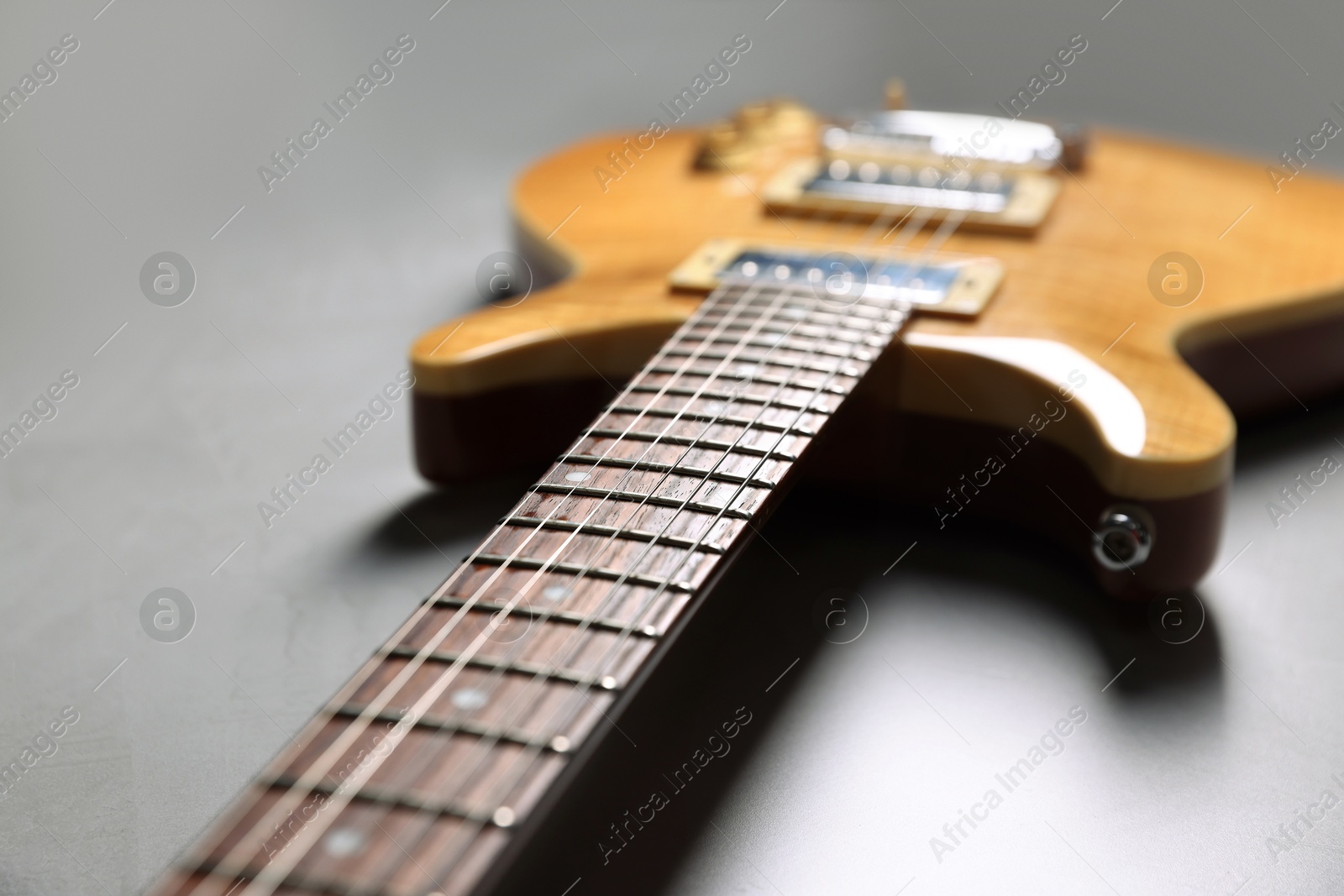 Photo of Modern electric guitar on grey background, closeup