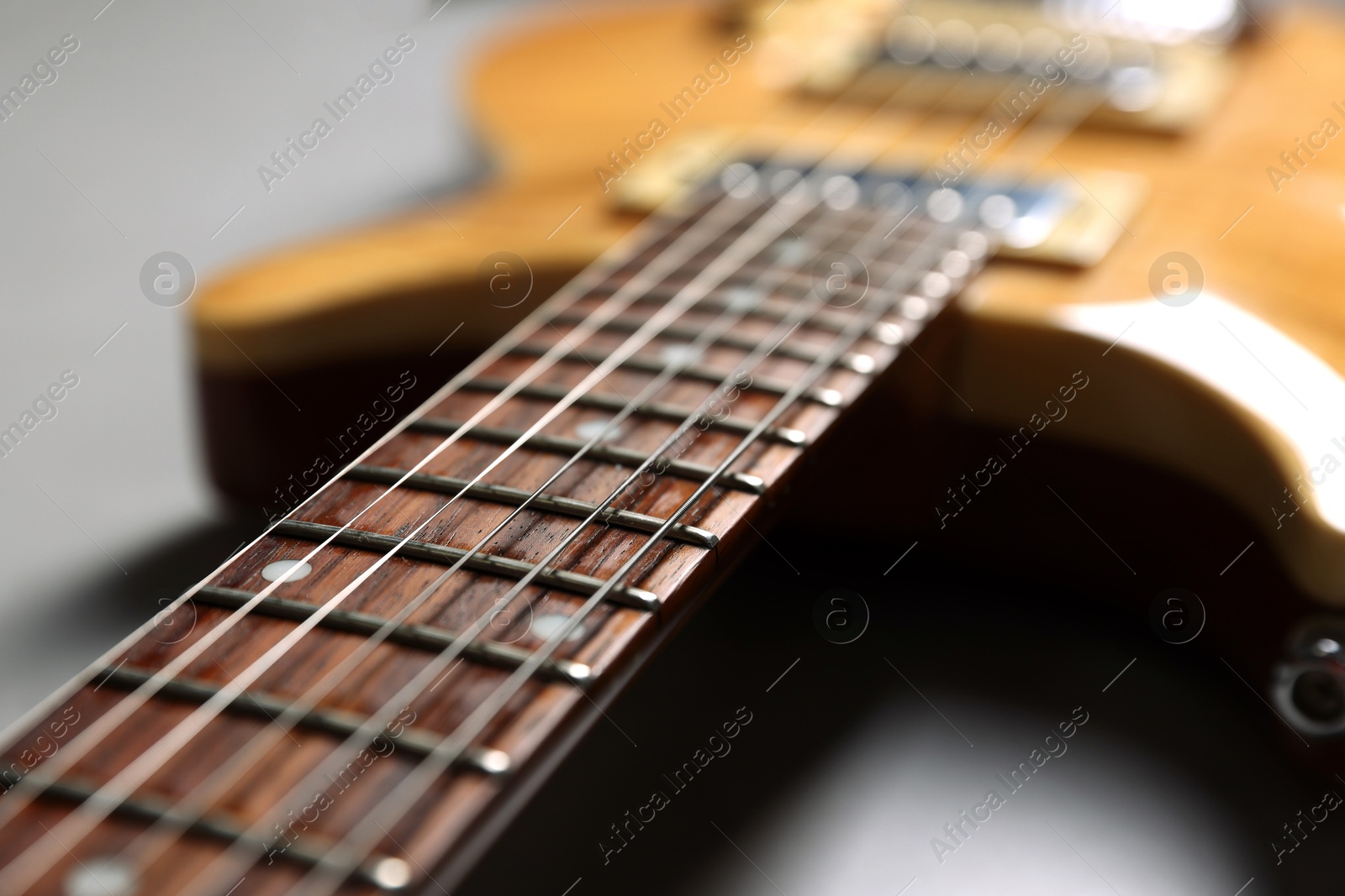 Photo of Modern electric guitar on grey background, closeup