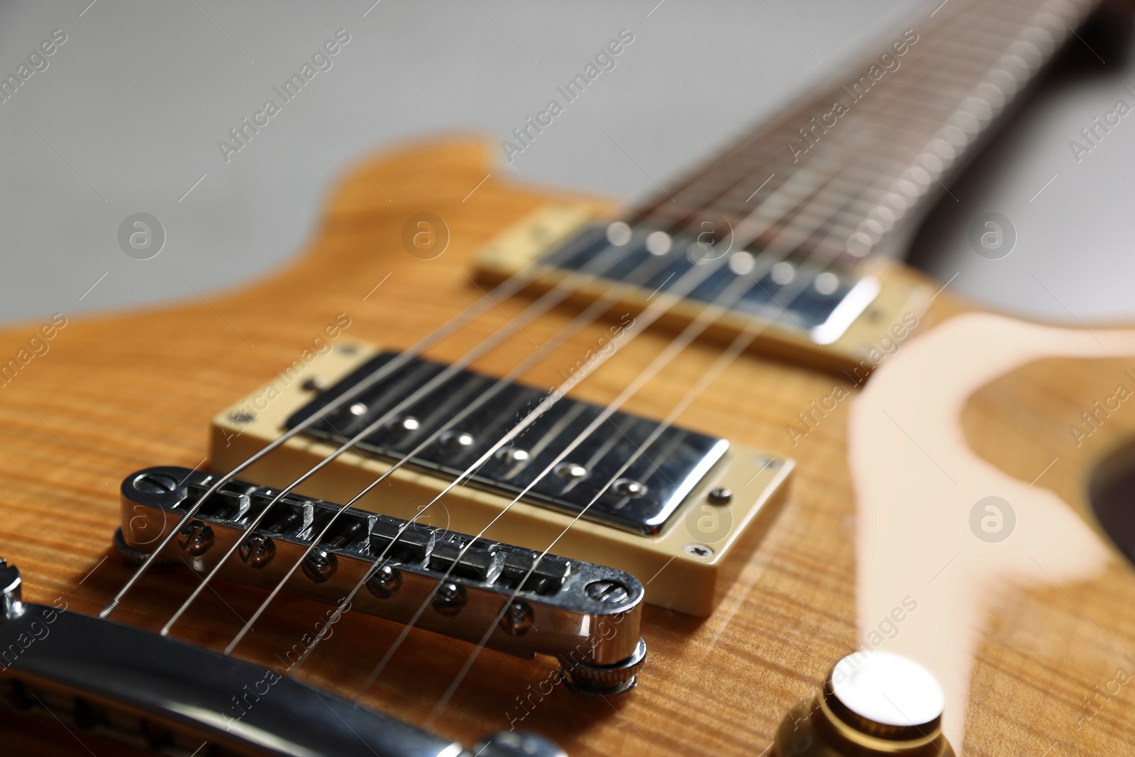 Photo of Modern electric guitar on grey background, closeup