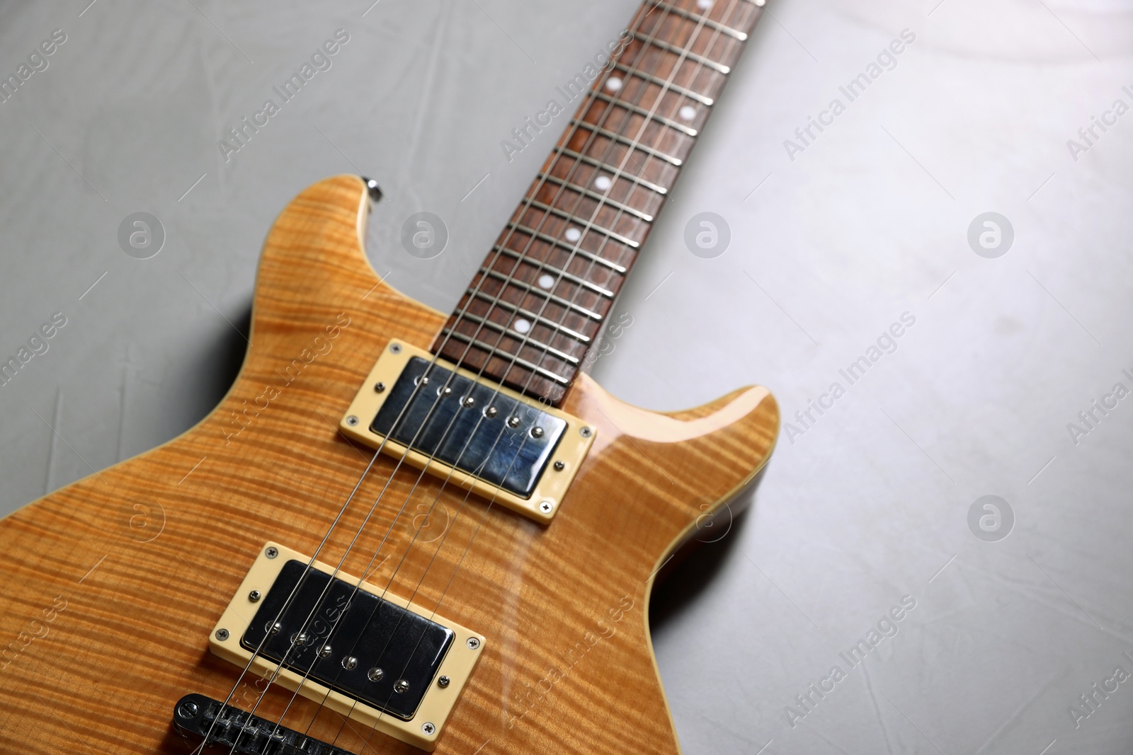 Photo of Modern electric guitar on grey background, closeup