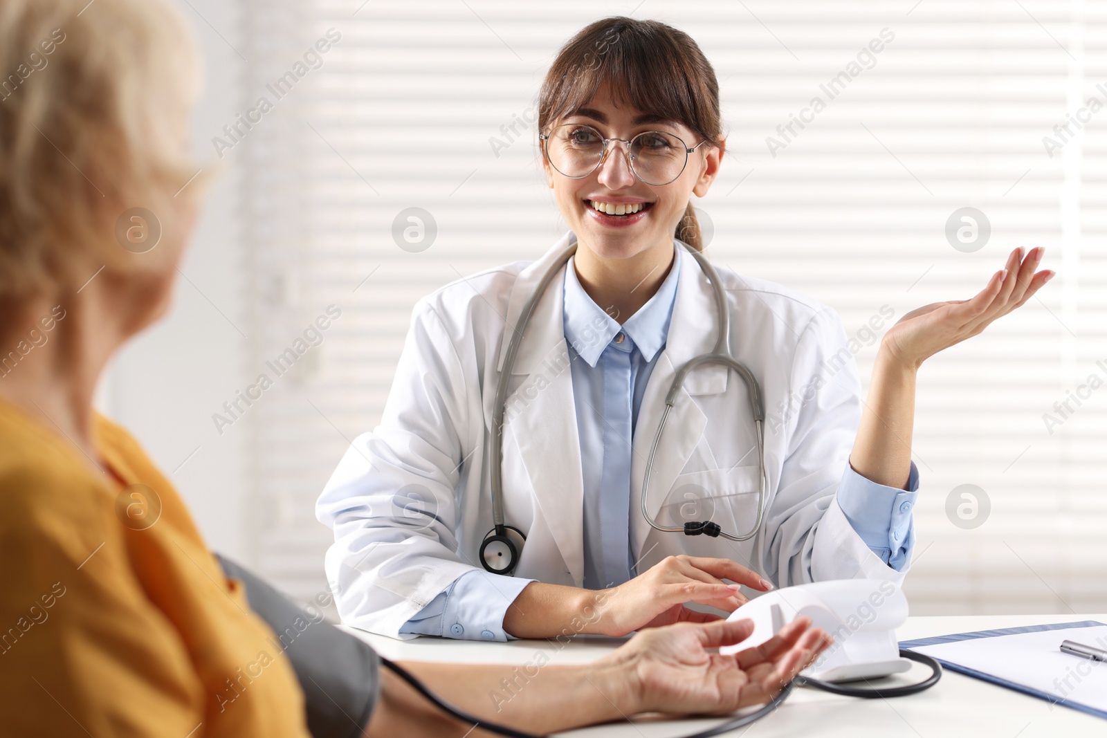 Photo of Doctor measuring senior woman's blood pressure during appointment in hospital