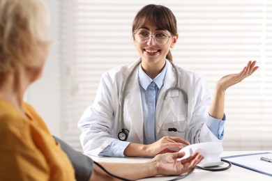 Photo of Doctor measuring senior woman's blood pressure during appointment in hospital