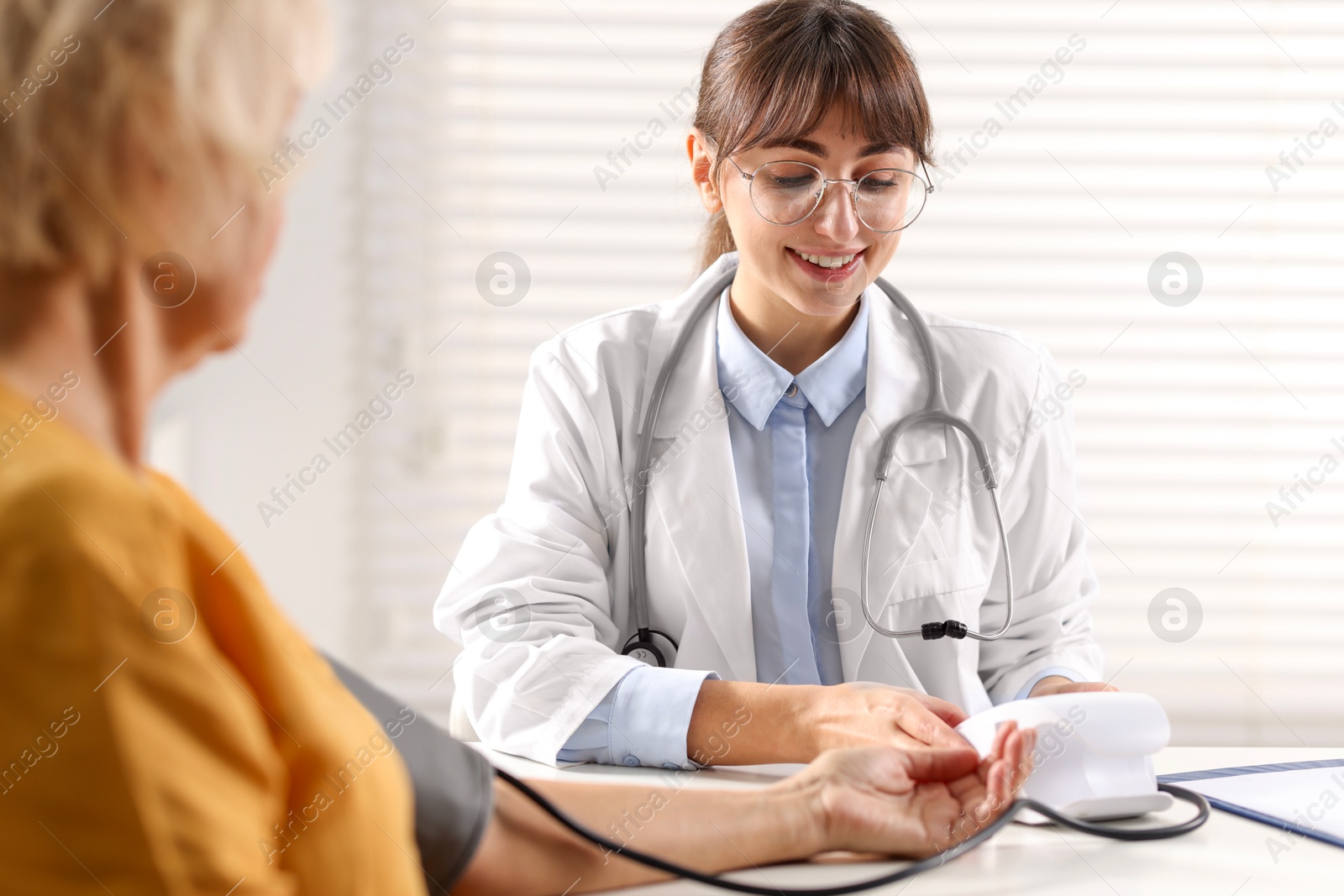 Photo of Doctor measuring senior woman's blood pressure during appointment in hospital