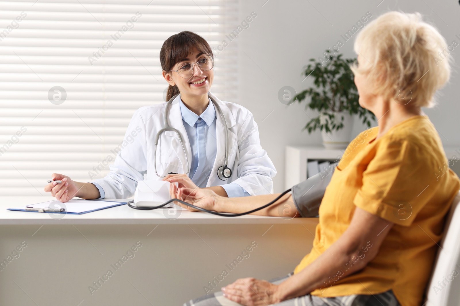 Photo of Doctor measuring senior woman's blood pressure during appointment in hospital