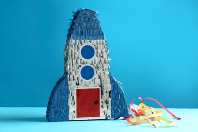 Photo of Bright pinata in shape of spaceship on blue background