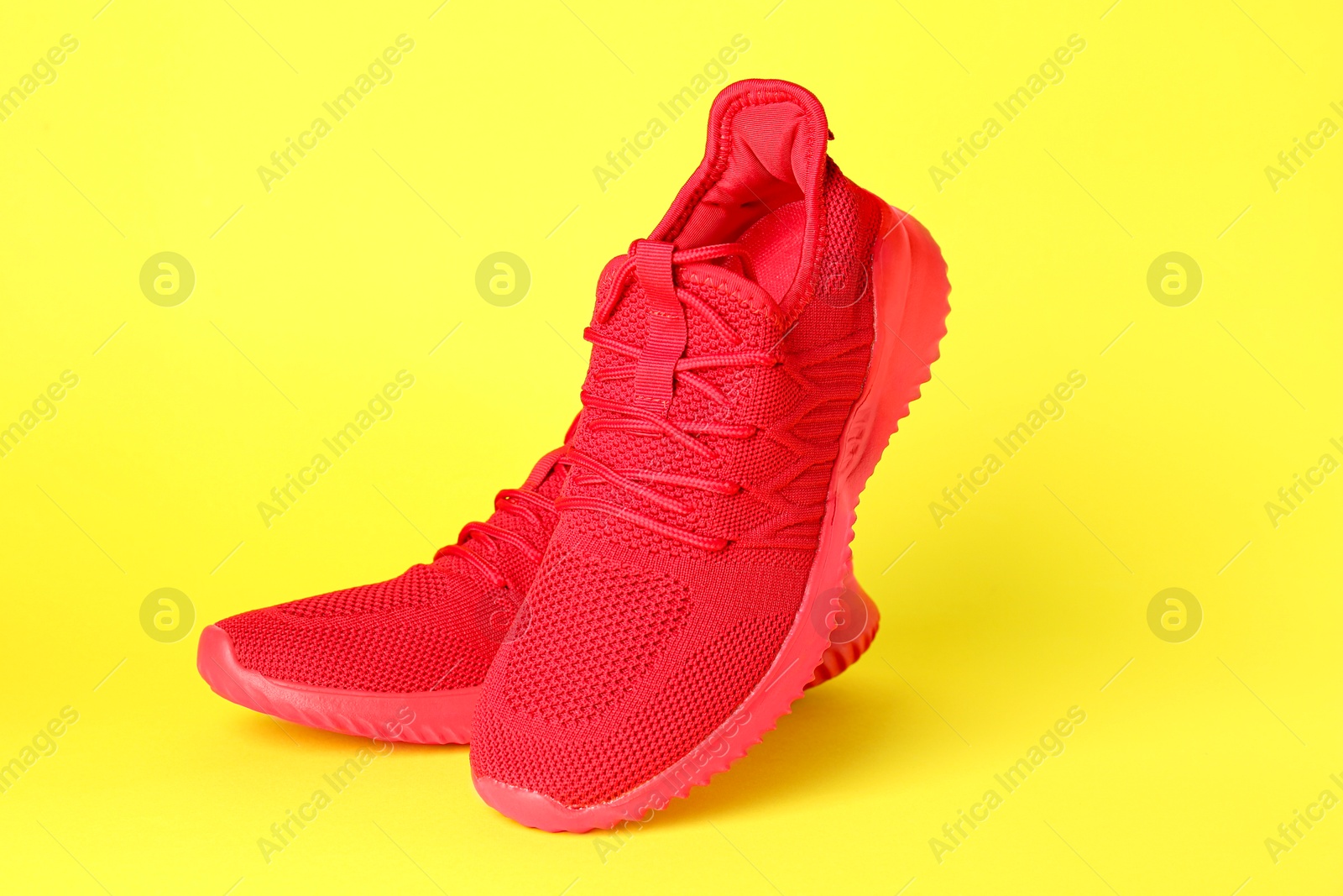 Photo of Pair of stylish red sneakers on yellow background