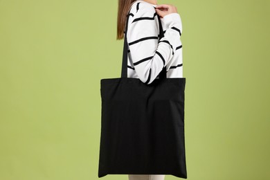 Photo of Woman with blank black shopper bag on color background, closeup. Mockup for design