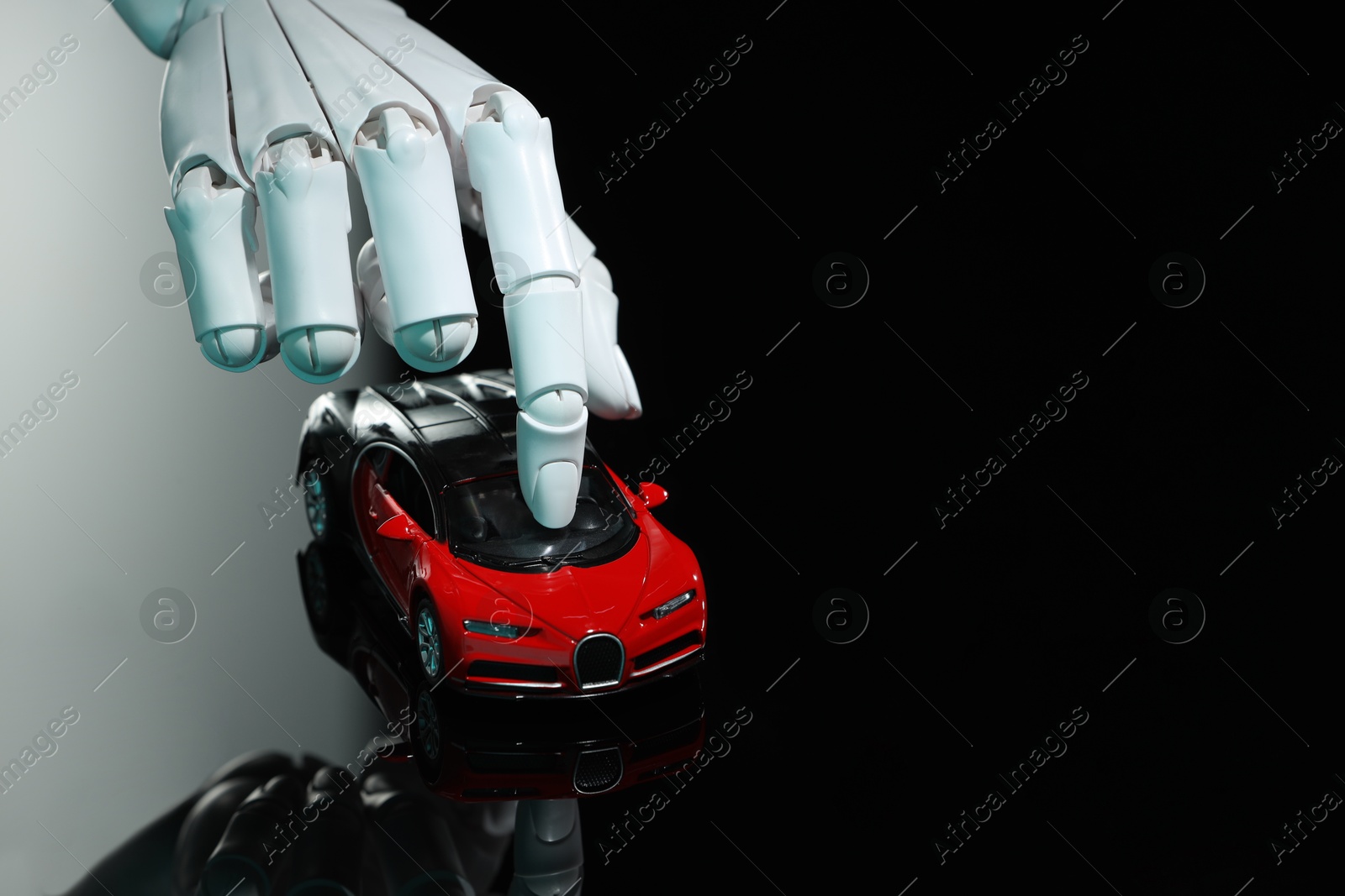 Photo of Artificial intelligence. Robot hand with toy car at black glass surface, closeup. Space for text