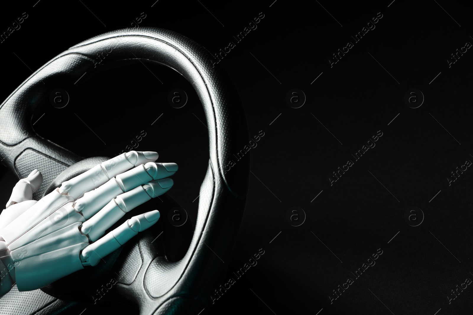 Photo of Artificial intelligence. Robot hand with steering wheel on black background, closeup. Space for text