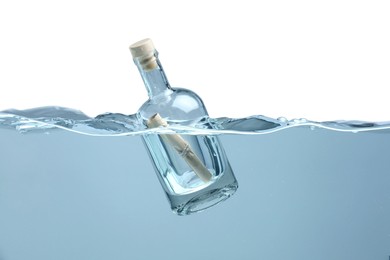 Photo of Corked glass bottle with rolled letter in water on white background